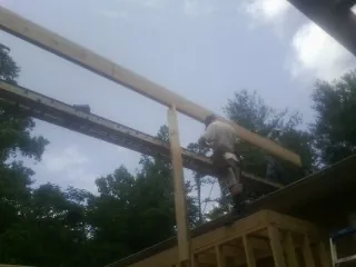 Carpenter setting a ridge beam over a new addition frame — Ice Dam Removal by Roofing Brothers in Sylva