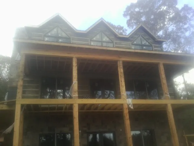 Dormers and porch framing on a large log home under construction — Roof Coating work by our crew in Sylva
