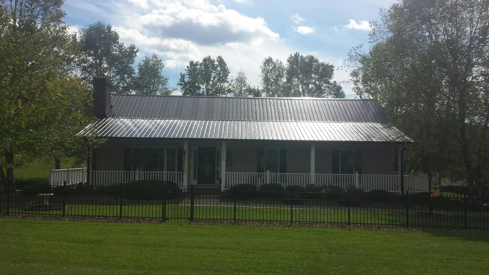 Gray metal roof on a brick ranch with a full width front porch — Gutter Guard Installation work by our crew in Sylva