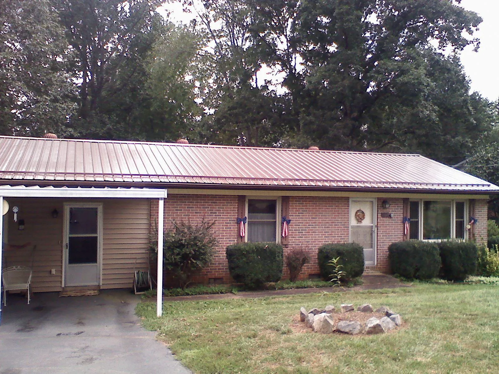 Bronze metal roof and carport on a brick ranch home — Roof Repair work by our crew in Sylva