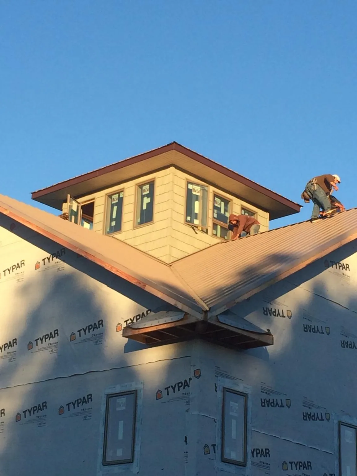 Roofers working around a rooftop cupola on a new metal roof at sunset — Roof Waterproofing in Sylva by Roofing Brothers
